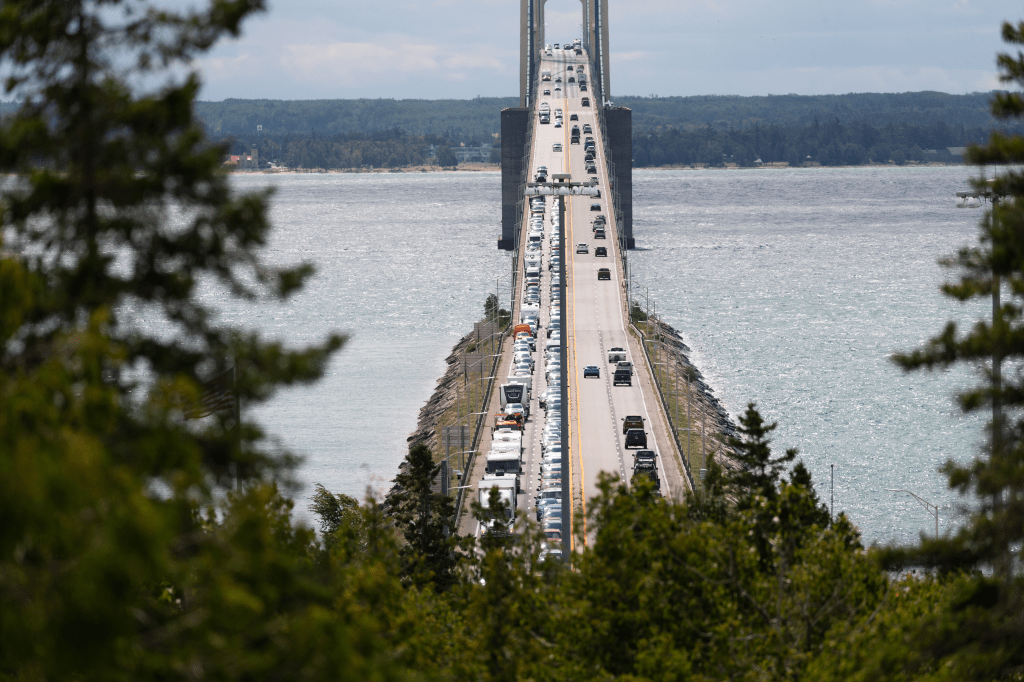 down the center of the Mackinac Bridge with traffic filing into town.