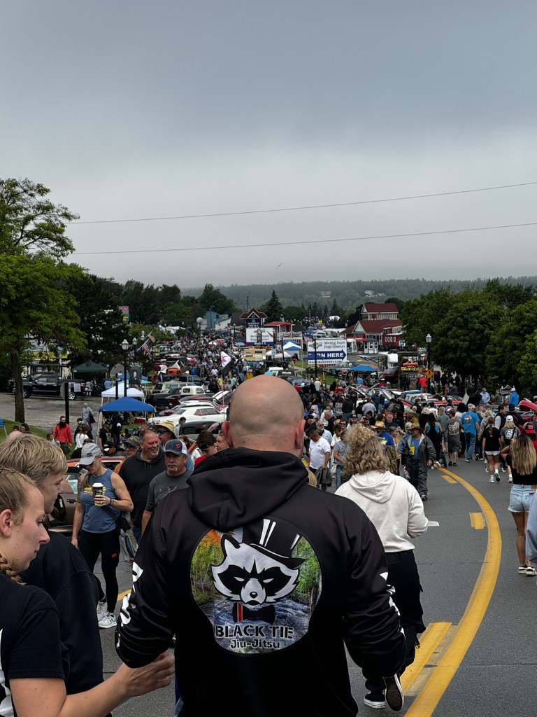 Large crowd of people walking down Main Street during a car show.